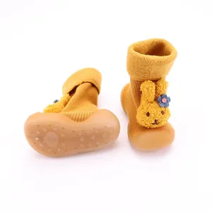Detalle de zapatos calcetín amarillos para bebé con conejo y suela de goma antideslizante