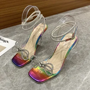 Close-up of rainbow high heel sandals featuring a crystal bow and clear straps.