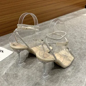 Close-up of elegant rhinestone wrap-around straps and clear wine-glass heels on sandals