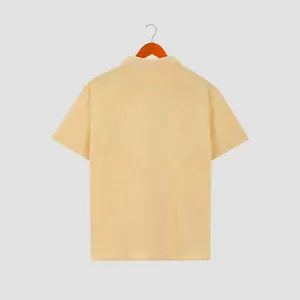 Detailed back view of a men's pale yellow waffle knit short-sleeved shirt on a wooden hanger