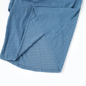 Close-up of blue waffle knit fabric texture and high-quality hem on a men's summer shirt.