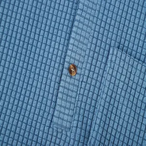 Macro detail showing blue waffle knit fabric texture and brown button on men's shirt