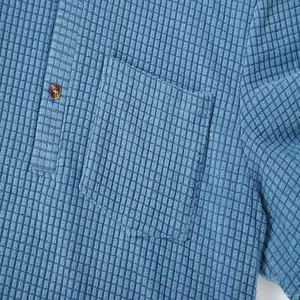 Close-up view of blue waffle texture fabric and pocket detail on a casual men's shirt