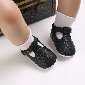 Detailansicht der schwarzen gewebten T-Strap Babyschuhe, getragen von einem Kleinkind mit Socken