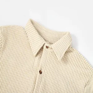 Close-up of a men's cream waffle knit shirt featuring a sharp lapel and brown buttons
