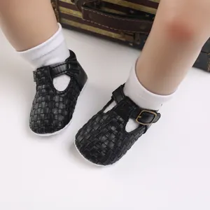 Nahaufnahme von gewebten schwarzen Baby-Lauflernschuhen mit T-Riemen und Schnallenverschluss.