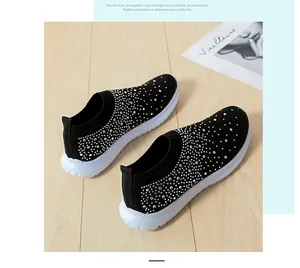 Schwarze Fly-Knit-Sneaker mit Strass-Details auf einem Holzboden
