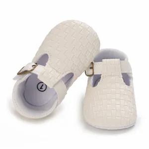 Nahaufnahme von weißen gewebten Babyschuhen mit weicher Sohle und Schnallendetail