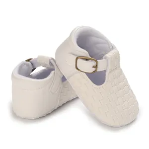 Nahaufnahme weißer gewebter Baby-Lauflernschuhe mit elegantem T-Riemen und Metallschnalle