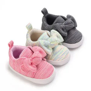 Adorable knitted infant walking shoes featuring a large bow in pink gray and white