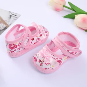 Close-up of pink floral baby pre-walker shoes with elegant ribbon bow and Velcro strap