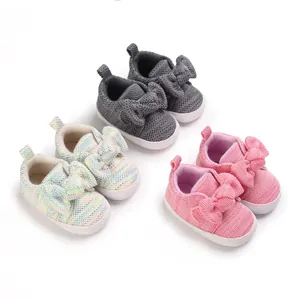 Close-up of adorable knitted baby shoes with large bows in pink, grey and rainbow colors