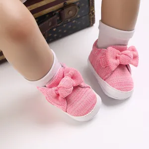 Detailed view of pink knit baby shoes with large bow for 0-1 year olds