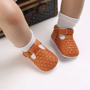 Nahaufnahme von braun geflochtenen T-Steg-Lauflernschuhen für Babys an Kinderfüßen
