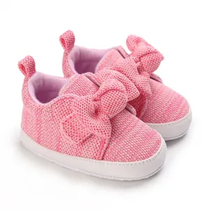 Close-up detail of soft pink knit baby walking shoes with a cute large bow design