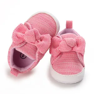 Close-up of pink knitted baby walking shoes featuring a large cute bow detail on the front