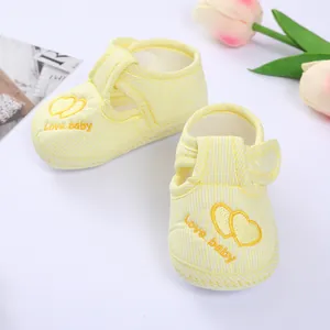 Detailed shot of yellow striped soft-sole baby shoes with heart embroidery