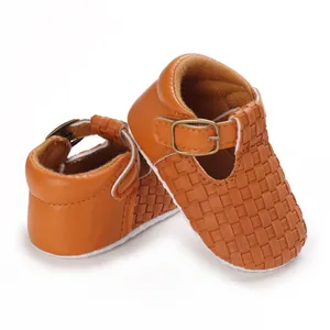Detailansicht von braunen geflochtenen Babyschuhen aus Leder mit Schnallenriemen.