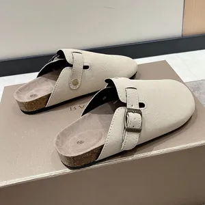 Detailed view of beige suede clogs featuring an adjustable buckle strap on a shoe box