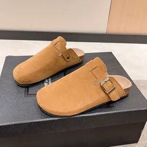 Detailed macro view of tan suede cork clogs featuring a vintage bronze metal buckle strap
