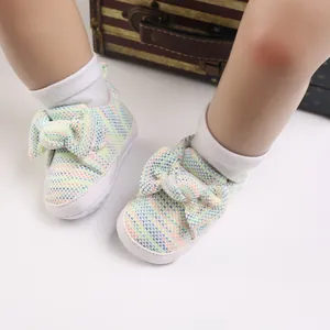 Detailed view of colorful knitted baby walking shoes with a large cute bow decoration.