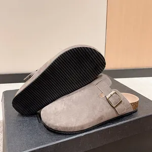Close-up of grey suede clogs showing the cork footbed and textured black rubber sole.