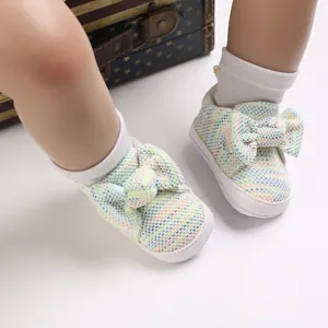 Detailed view of baby walking shoes with colorful woven fabric and a large bow detail.