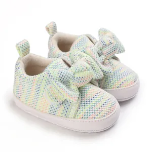 Close-up of cute multicolored knitted baby walking shoes with a large bowknot detail