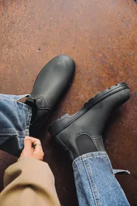 Gros plan de bottines Chelsea gris mat sur une surface métallique industrielle rustique