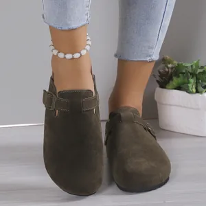 Close-up view of olive green suede clogs featuring an adjustable metal buckle strap.