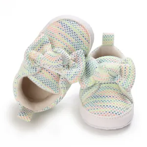 Close-up of colorful knitted baby walking shoes with large decorative bow detail.
