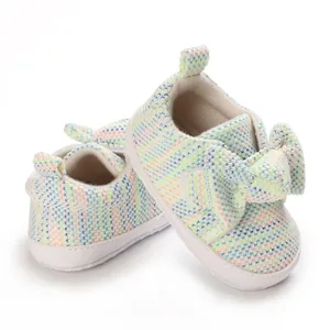 Detail of baby walking shoes featuring colorful knit texture and a large decorative bow