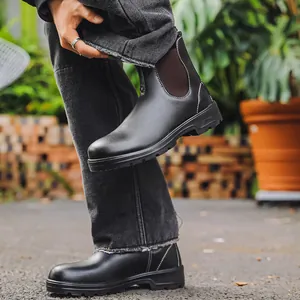 Vue détaillée de bottines Chelsea noires avec surpiqûres blanches et semelles crantées.