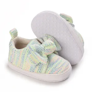 Detailed view of soft-sole baby shoes featuring a colorful knit pattern and a large bow