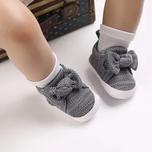 Close-up detail of soft-soled grey knitted baby walking shoes featuring a cute bow