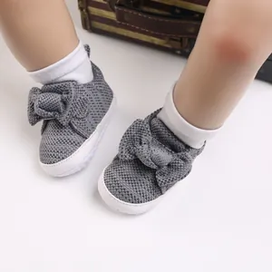 Detail of grey knitted baby shoes featuring a large soft bowknot and white non-slip soles