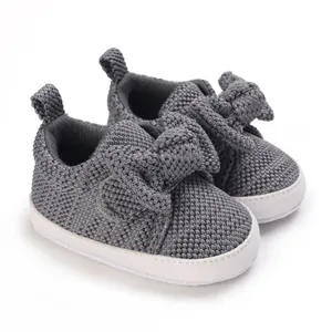 Detailed view of grey knitted baby walking shoes featuring a large decorative bow