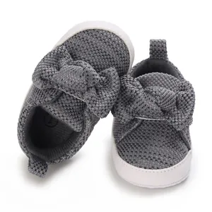 Close-up of grey knitted baby walking shoes featuring a large bowknot decorative detail