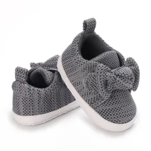 Detailed close-up of grey knitted baby shoes with cute bow decoration