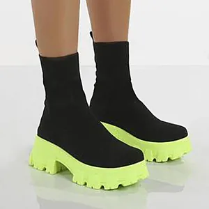 Gedetailleerde weergave van zwarte gebreide dameslaarzen met een neon groen platform zool.
