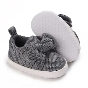 Soft knitted infant walking shoes with a cute bow and non-slip sole detail.