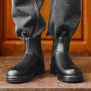 Gros plan de bottines Chelsea classiques en cuir noir mat portées avec un jean gris