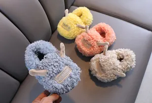 Dettaglio di pantofole in peluche per bambini con corna carine e fodera calda e morbida.