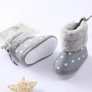 Vista detallada de botas de invierno para bebé con lunares y ribete de piel sintética.