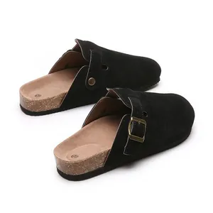 Close-up of black suede closed-toe clogs with adjustable buckle and cork sole