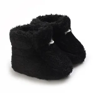 Gros plan de bottines bébé en peluche noire montrant la texture polaire douce et chaude.