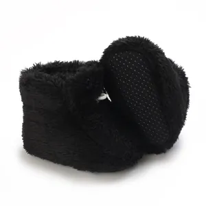Gros plan de bottines de bébé noires en peluche pour l'hiver avec semelles antidérapantes