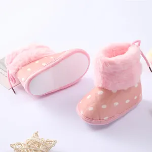 Detalle de botas rosa con lunares para bebé, borde de pelo sintético y suela antideslizante.