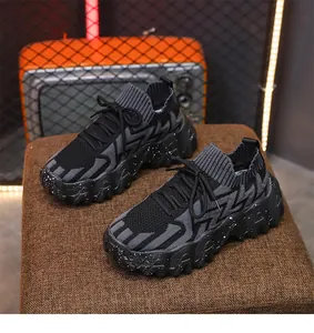 Primer plano de zapatillas gruesas de punto negro y gris con suelas salpicadas.