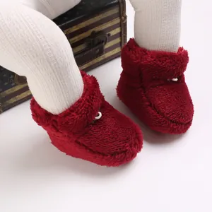 Détail de bottines d'hiver en peluche rouge pour bébé, texture douce et chaude.